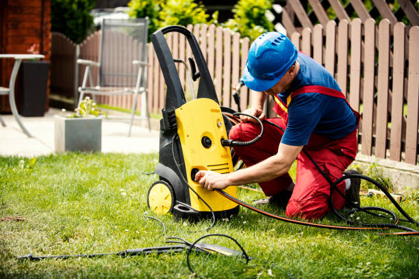 Man connecting hose to an electric pressure washer on the lawn.