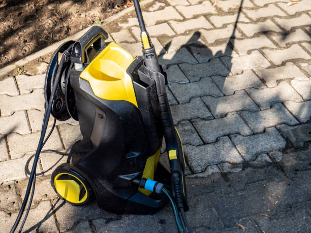 Yellow and black electric pressure washer on pavers.