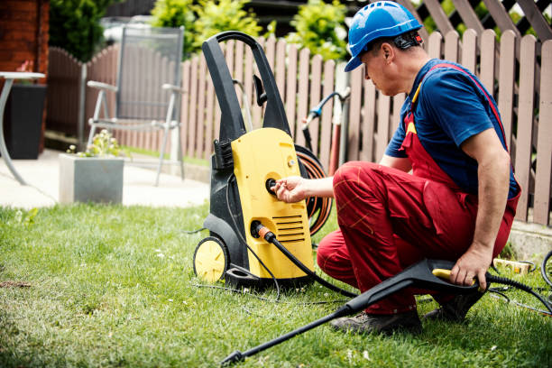 Man assembling an electric pressure washer's spray gun on a grassy backyard.