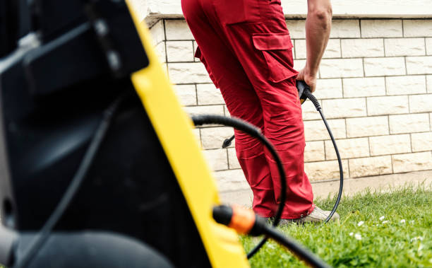 Person in red pants setting up an electric pressure washer for outdoor cleaning.